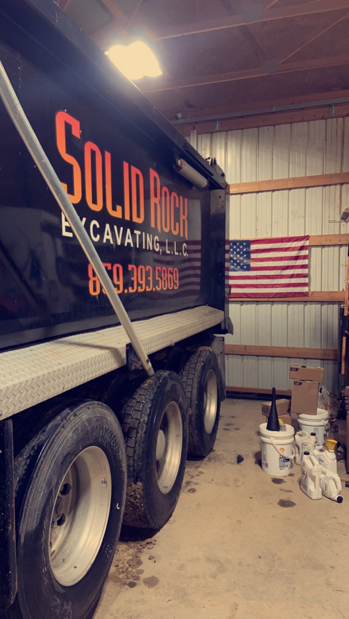 Solid Rock Excavating dump truck parked in the shop beside an American flag